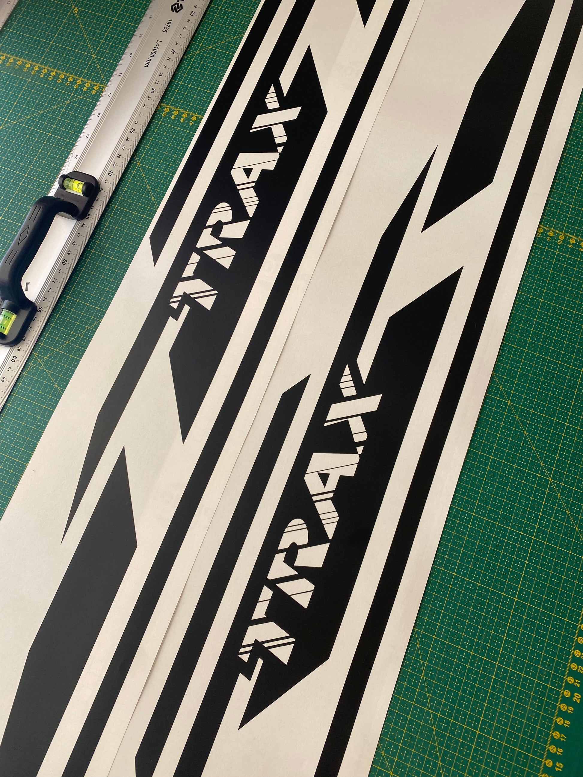A set of black and white geometric design stickers for a Chevrolet Trax, displayed on a measuring tape against a green background.
