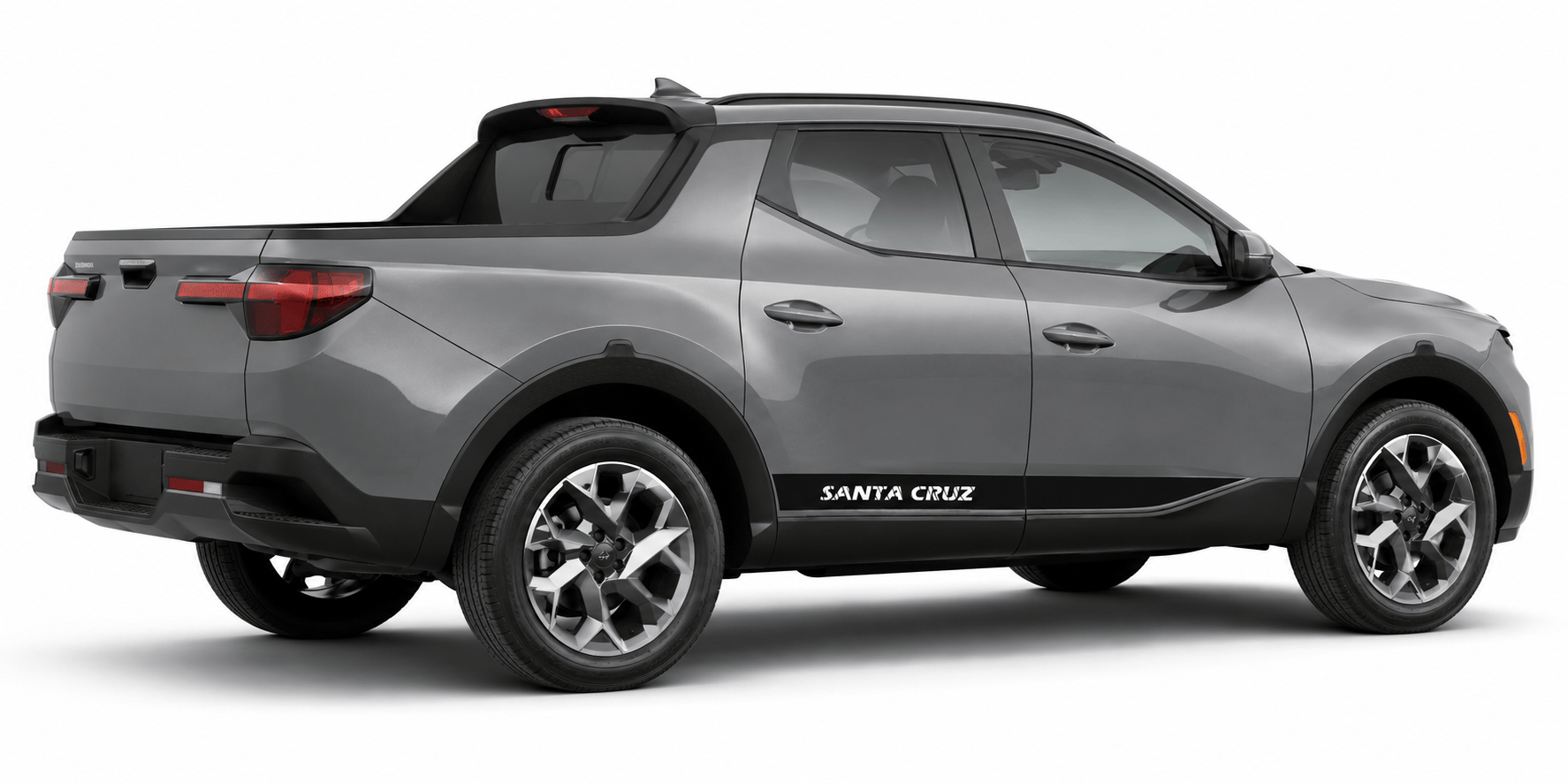 A gray compact pickup truck shown from a three-quarter rear angle on a clean white background. The vehicle has black trim along the lower body and side, silver multi-spoke wheels, and 'SANTA CRUZ' printed in white on the side panel.