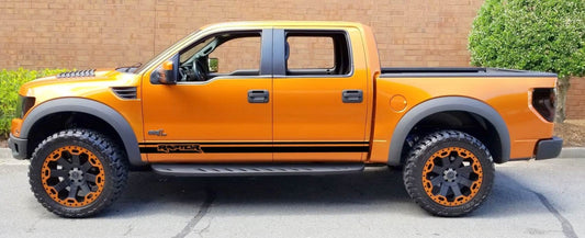 The image shows a orange Ford F-150 pickup truck with a set of premium vinyl stickers designed for the vehicle. The stickers are featured on the truck's bed and sides, showcasing a bold orange color and a design that includes American flag line stripes.