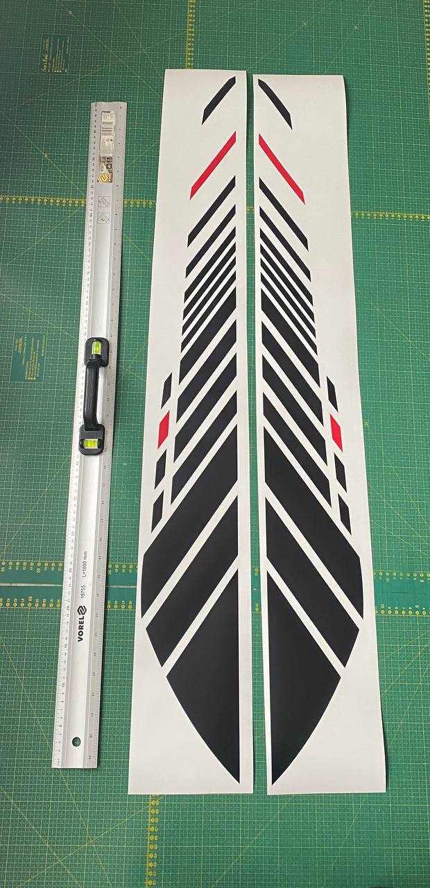 Two black and red striped decal sheets on a green cutting mat with a ruler.